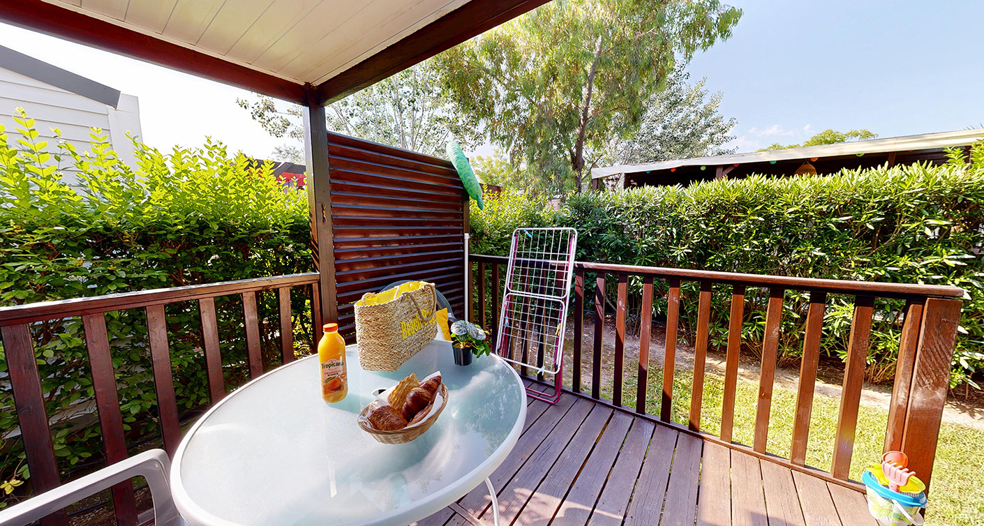 Buitenkant van de klassieke stacaravan van 24 m² voor 2 personen met half-overdekt terras, te huur op de 4-sterrencamping Le Neptune in de Hérault.