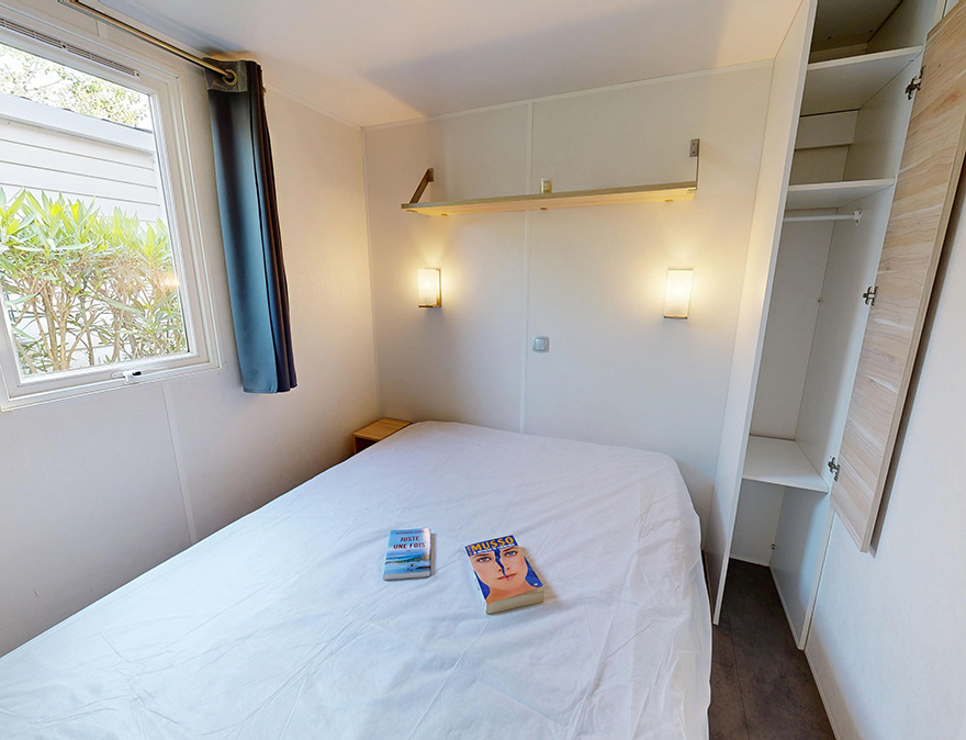 Slaapkamer met 1 tweepersoonsbed in de klassieke stacaravan van 24 m² voor 2 personen te huur op de 4-sterrencamping Le Neptune in Agde
