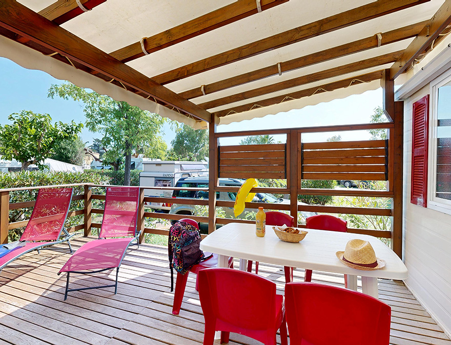 Het half-overdekte terras met tuinmeubels van de klassieke stacaravan van 25 m² voor 5 personen, te huur op de 4-sterrencamping Le Neptune in de Hérault.