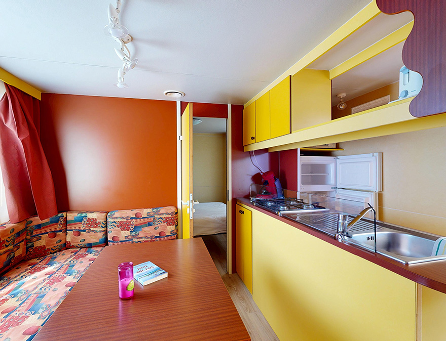 De keuken en zithoek van de klassieke stacaravan van 25 m² voor 5 personen, te huur op de 4-sterrencamping Le Neptune in Agde.