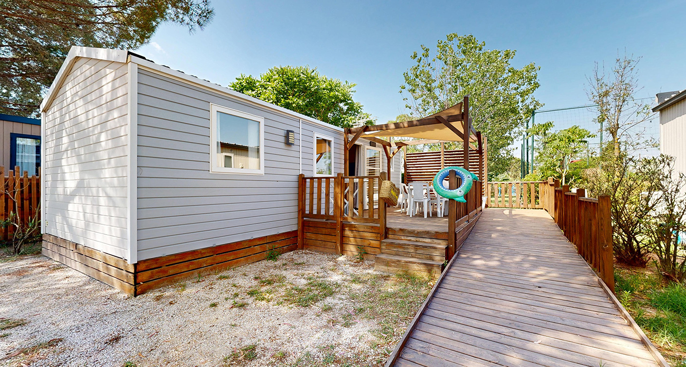 Außenansicht des Mobilheims PMR (für Personen mit eingeschränkter Mobilität) Premium 33 m² für 4/6 Personen mit halbüberdachter Terrasse, zu mieten auf dem 4-Sterne-Campingplatz Le Neptune im Departement Hérault